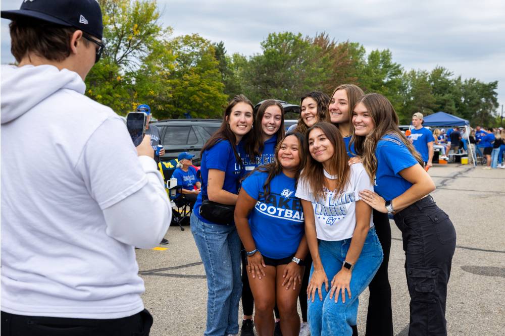 Attendee takes a picture of group of people during Family Day tailgate.